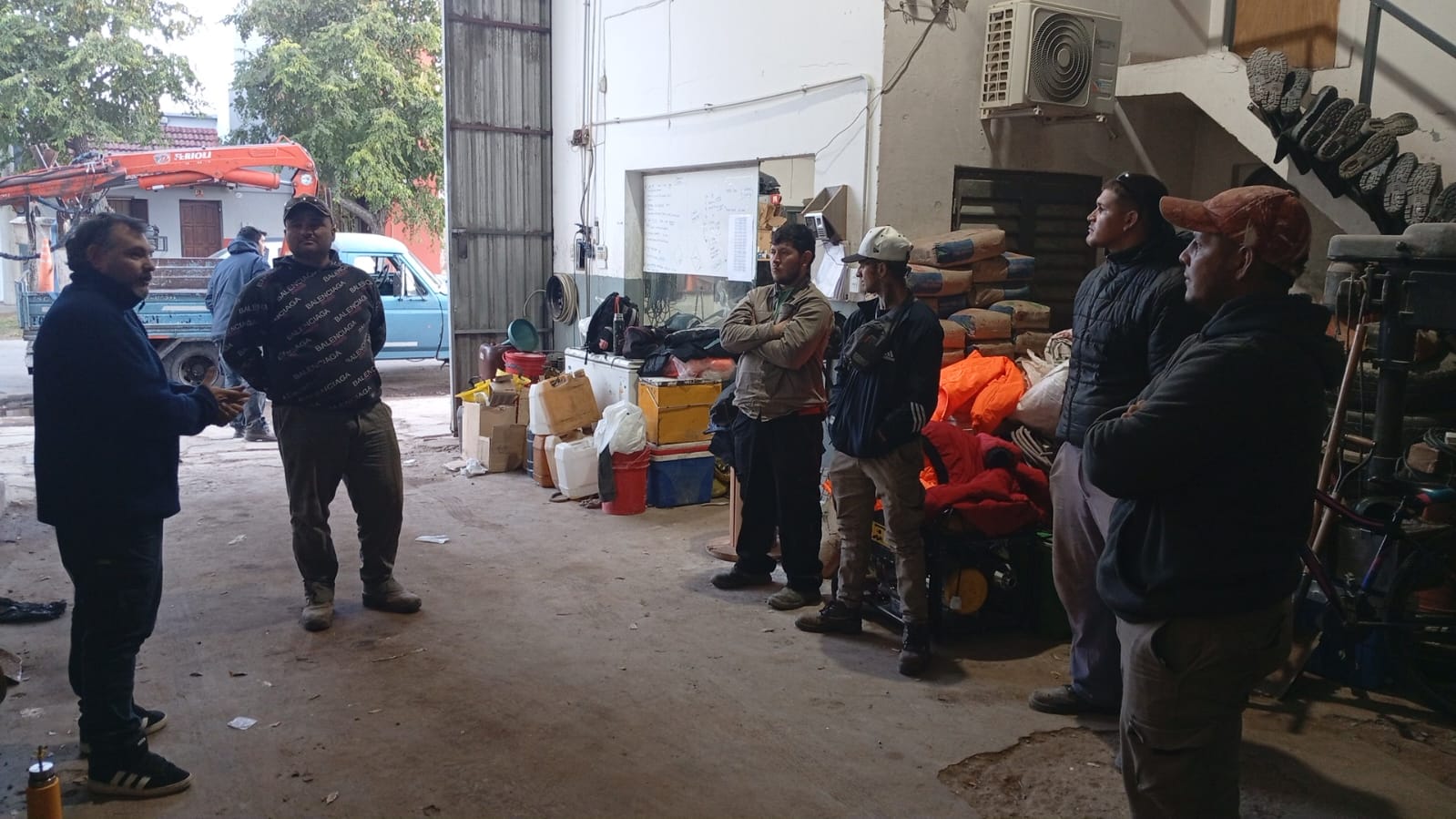 Conversación con trabajadores cerca de la entrada de un taller.