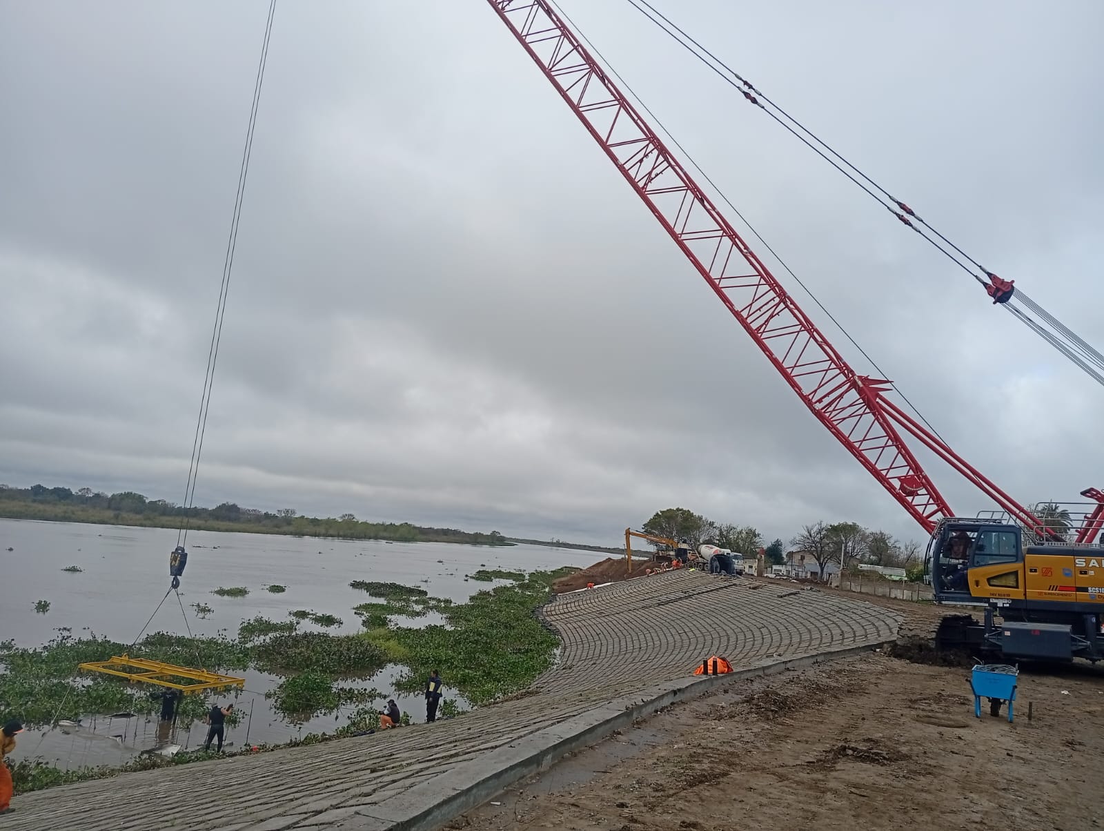 Grúa y equipo de trabajo en una obra sobre la ribera.