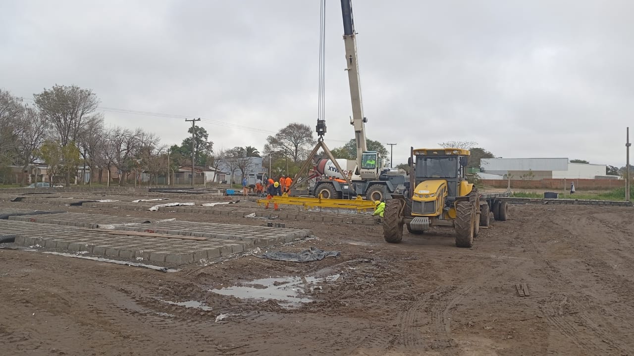Grúa, tractor y personal en una zona de trabajo con elementos de hormigón.